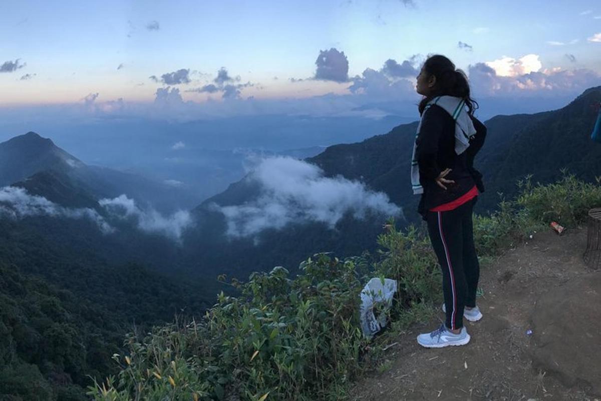 a woman standing on top of a mountain overlooking a valley