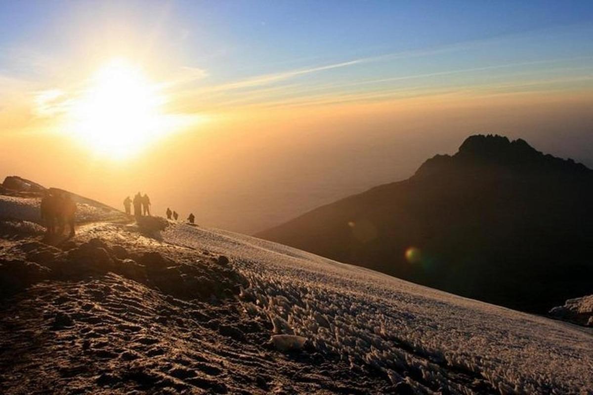 sekumpulan orang berdiri di atas gunung pada waktu matahari terbenam