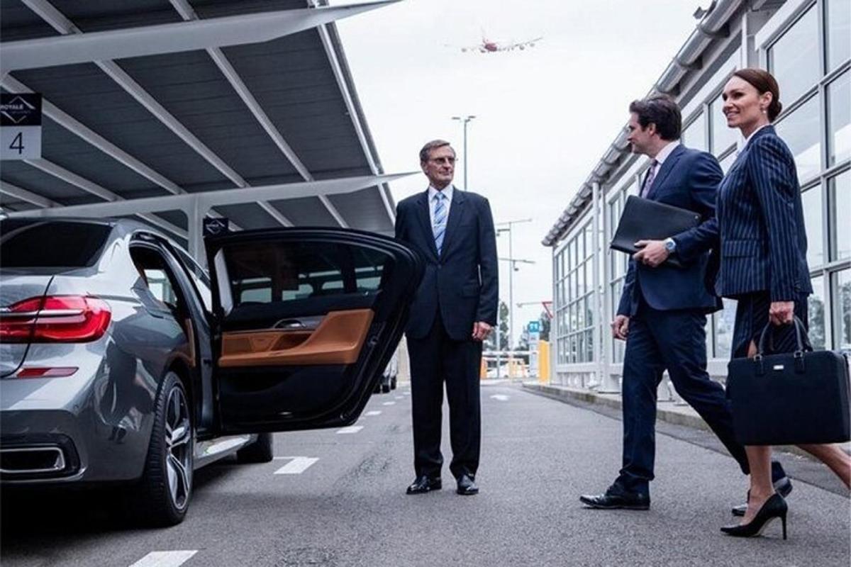 tři muži v oblecích stojí vedle auta
