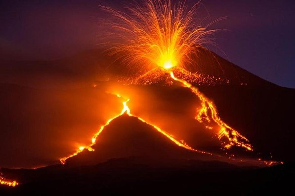 Una montaña con una erupción de fuego por la noche.