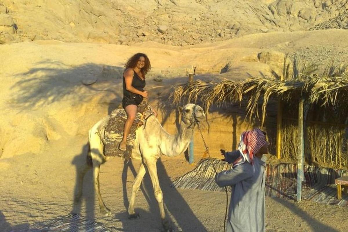 امرأة تركب الجمل بينما يلتقط الرجل صورة