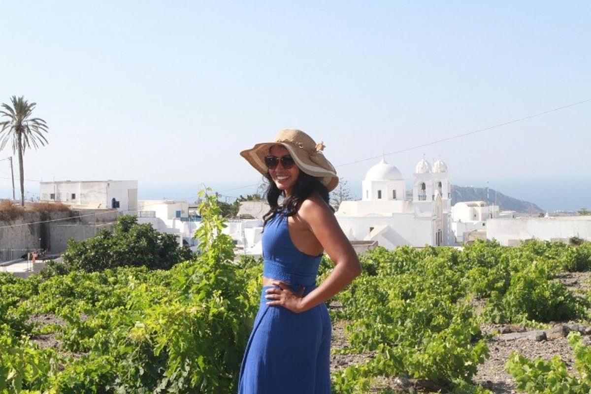 una donna con un vestito blu e un cappello in piedi in un vigneto