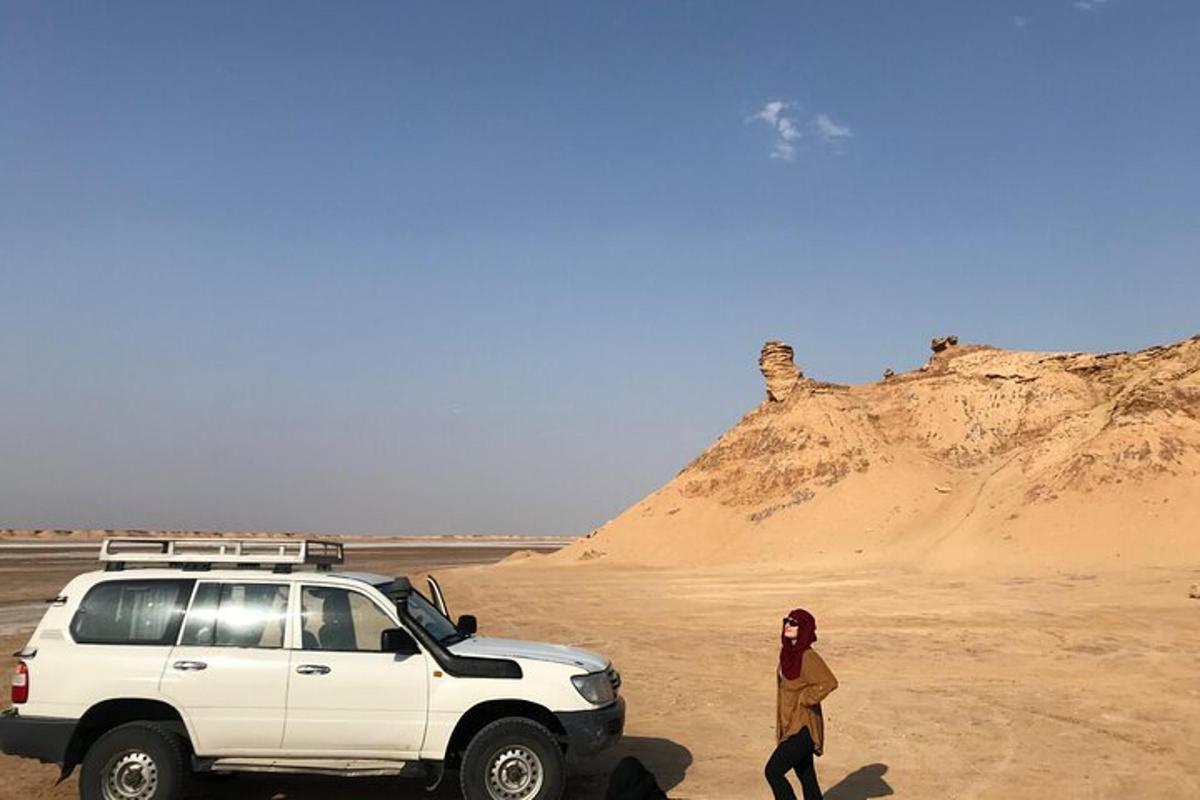 a woman standing next to a white suv in the desert