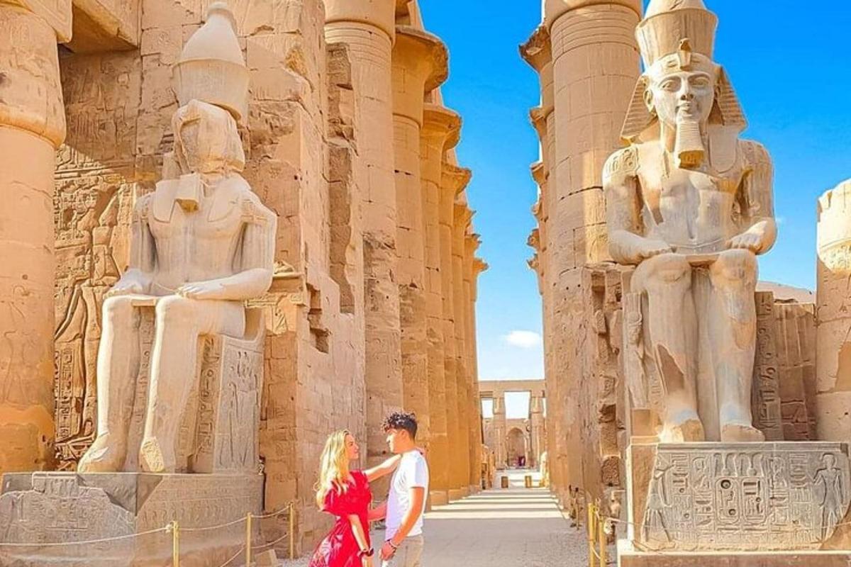 duas pessoas em pé em frente a uma estátua