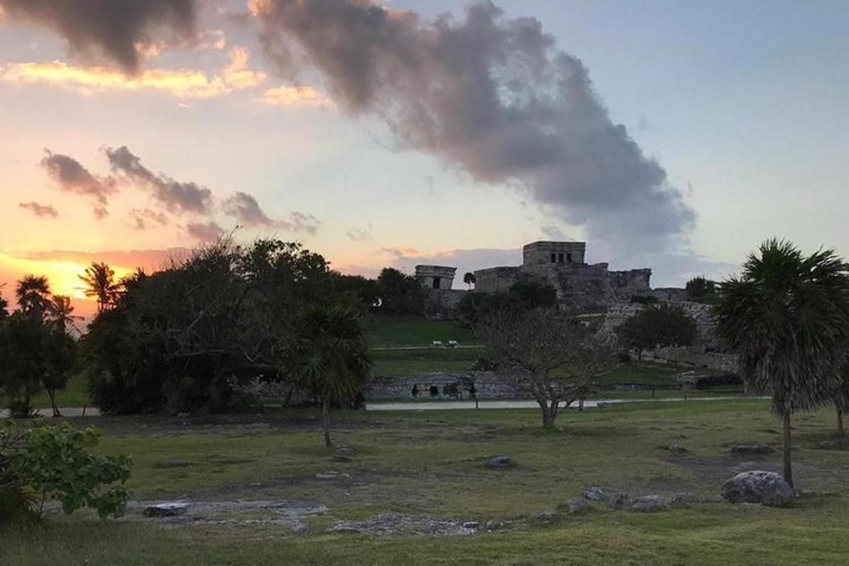 Una puesta de sol en un parque con un castillo al fondo