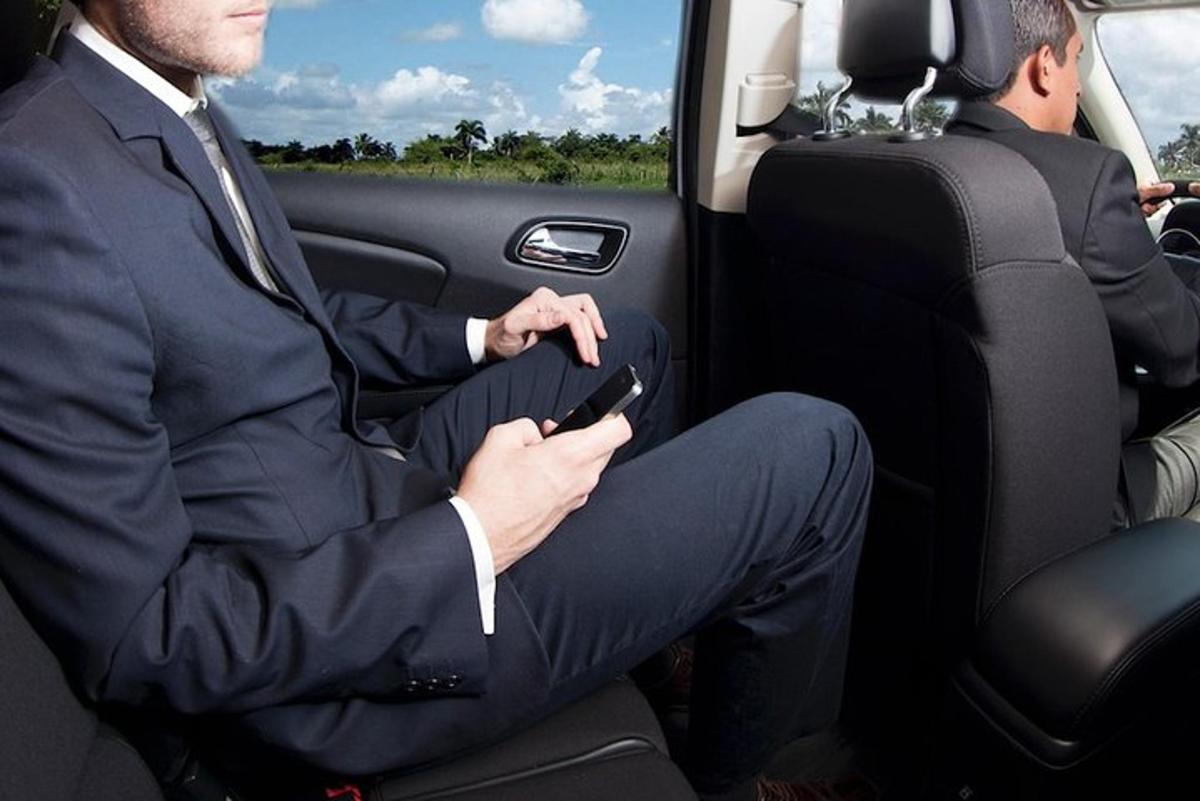 un uomo in giacca e cravatta seduto in macchina con un cellulare