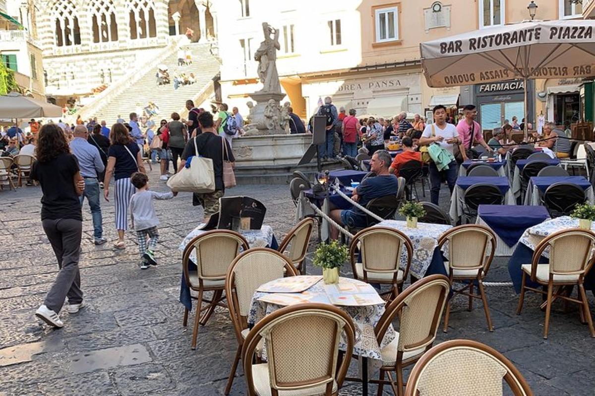 eine Gruppe von Menschen, die an Tischen vor einem Brunnen sitzen