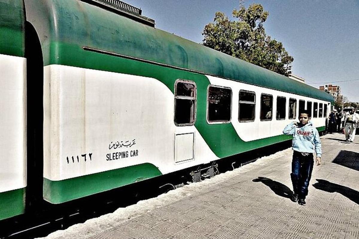 seorang lelaki berjalan di sebelah kereta api hijau dan putih