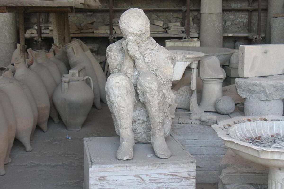 Una estatua de un hombre de pie delante de jarrones.