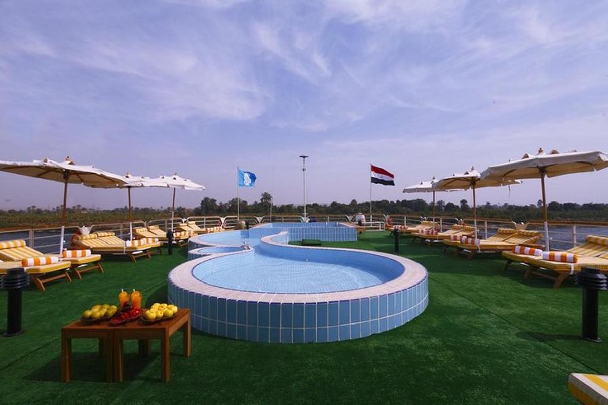 una piscina con sillas y sombrillas en el césped