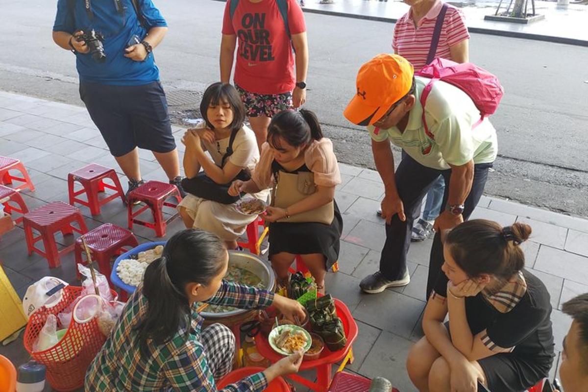 sekelompok orang yang duduk mengelilingi meja dan makan makanan