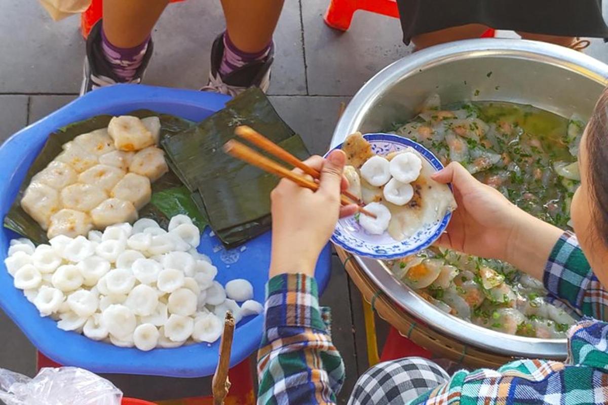 seseorang yang memegang sepiring makanan di samping panci makanan