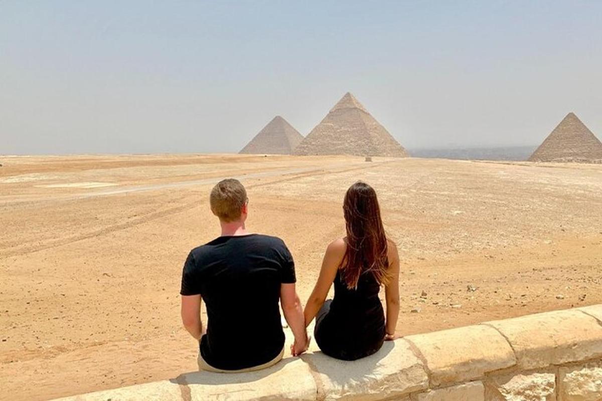 muž a žena sedící na zdi a dívající se na pyramidy