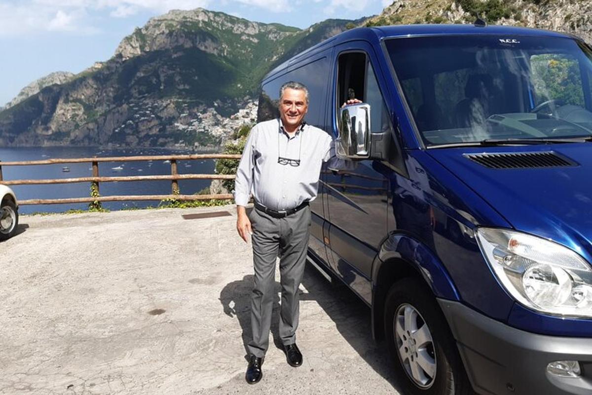 Un hombre está parado junto a una camioneta azul.
