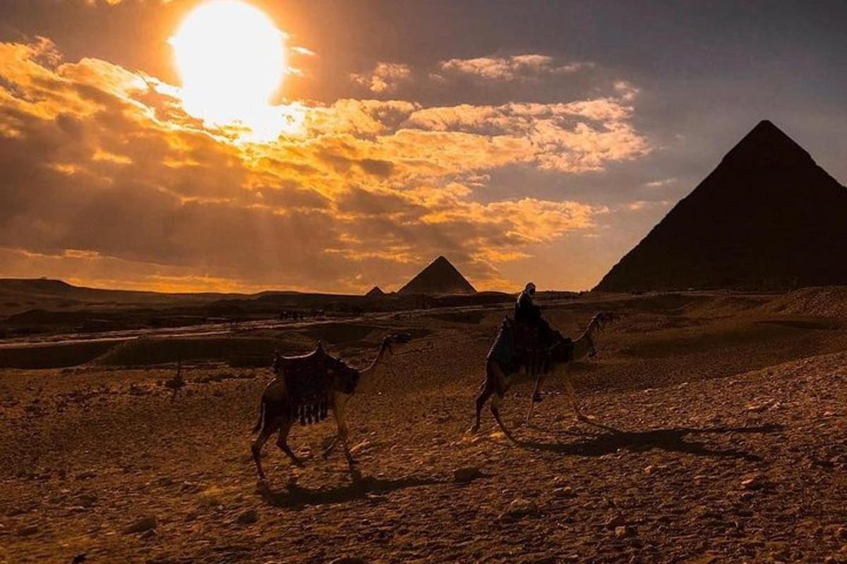 isang taong nakasakay sa isang kamelyo sa disyerto kasama ang mga piramide