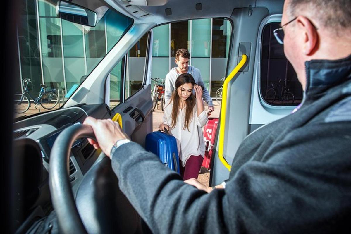 a man driving a bus with a woman with luggage