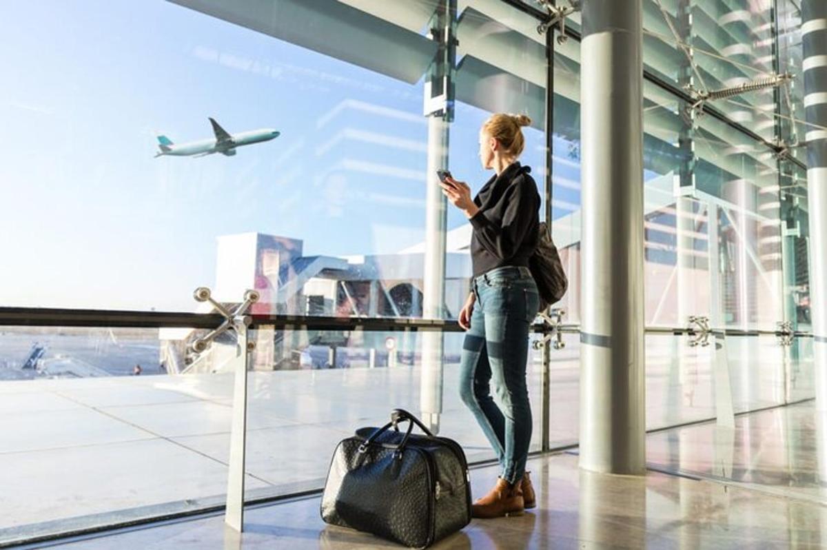 uma mulher olhando para o celular em um aeroporto