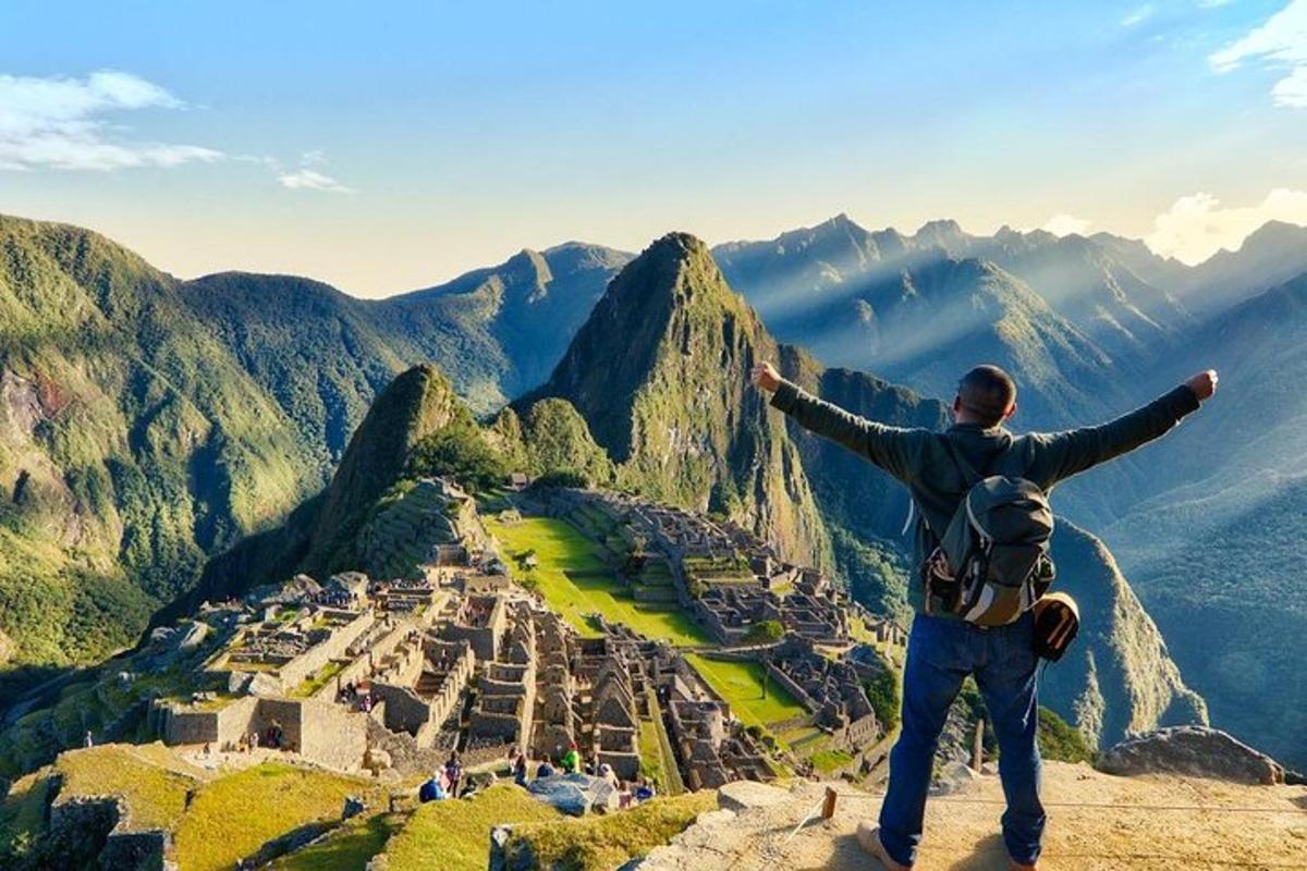 Un hombre parado en la cima de una montaña con los brazos extendidos.