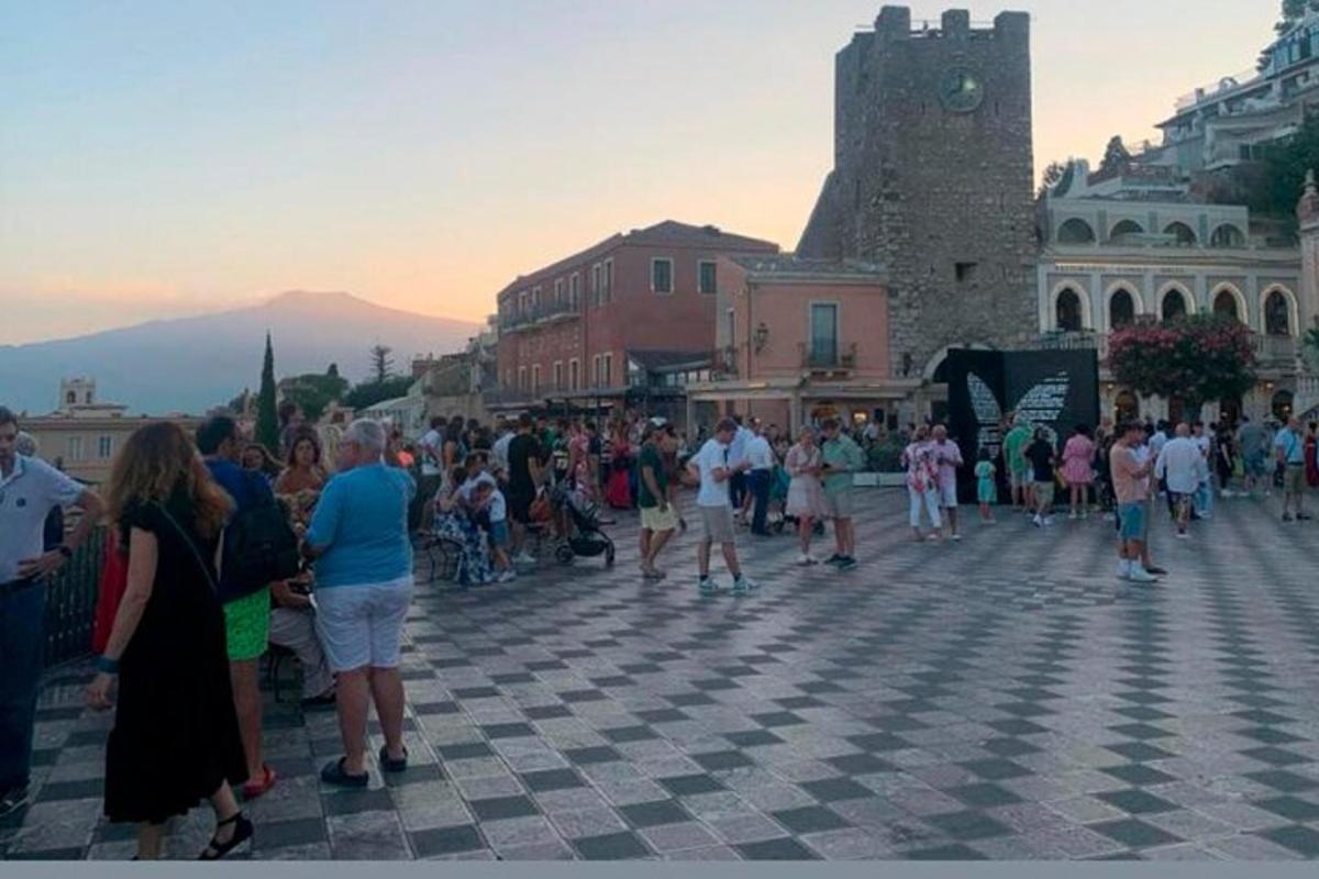 a crowd of people standing in a square with a clock tower