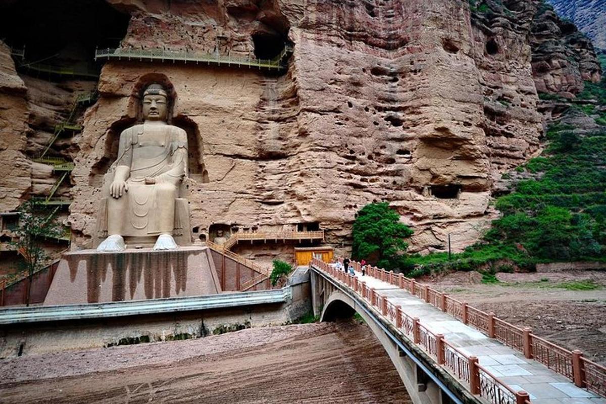 a large statue on a bridge next to a mountain