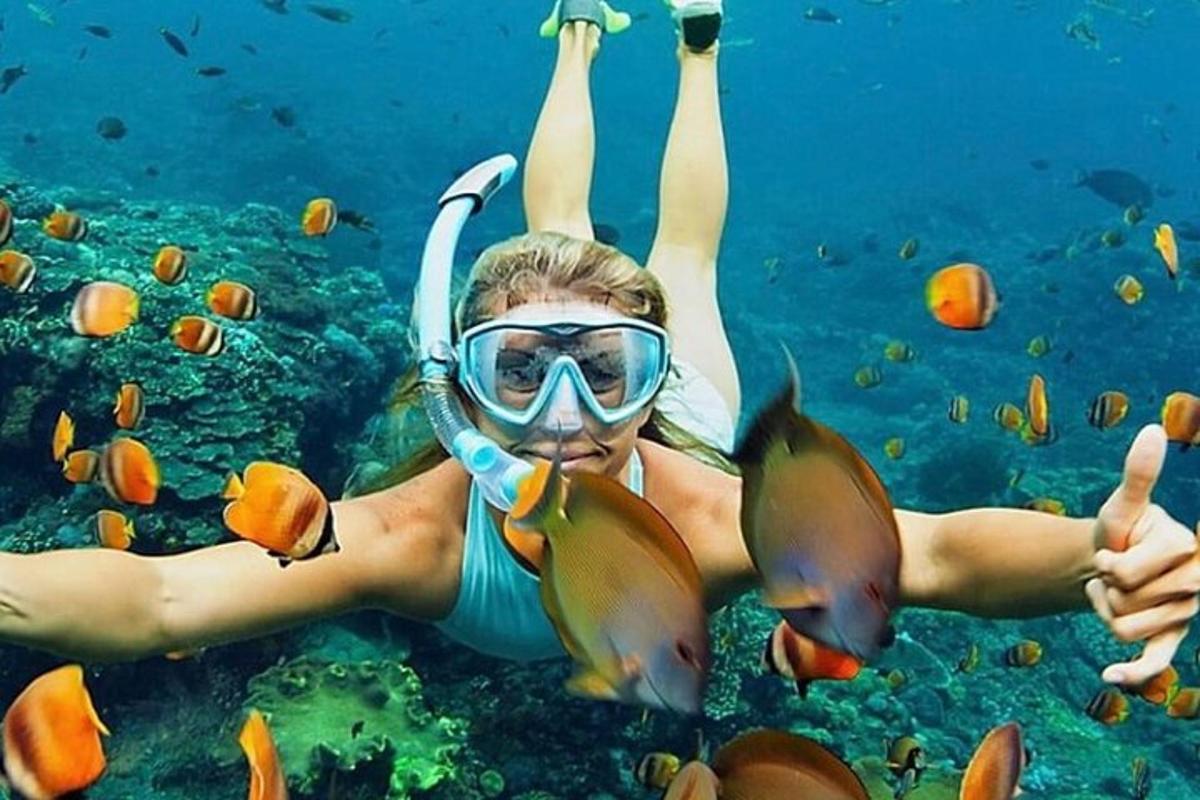 una donna con un boccaglio e un pesce nell'acqua
