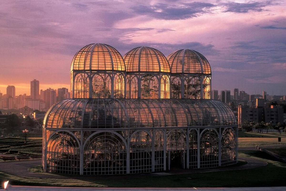 a large glass greenhouse with a city in the background