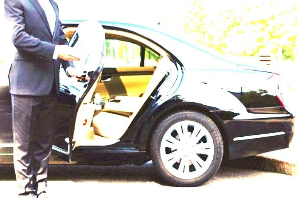 un uomo in giacca e cravatta che apre la portiera di un'auto