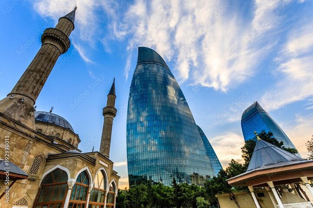 a tall glass building next to a mosque and a tower
