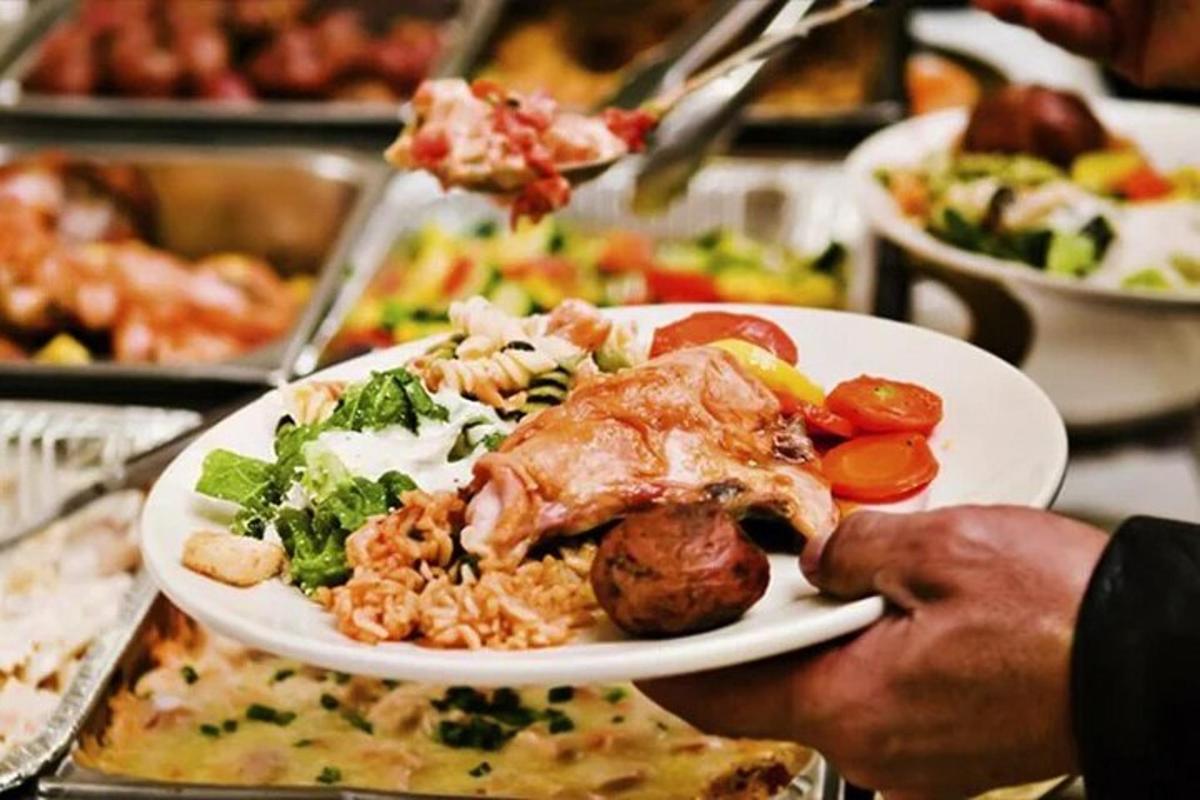 una persona que sostiene un plato de comida sobre una mesa