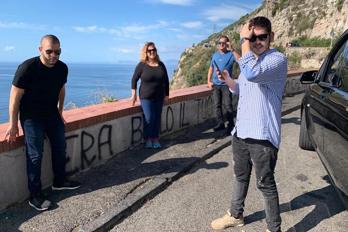 um grupo de pessoas em pé em uma estrada perto do oceano