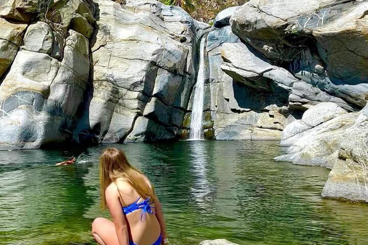 seorang wanita berbikini berdiri di hadapan air terjun