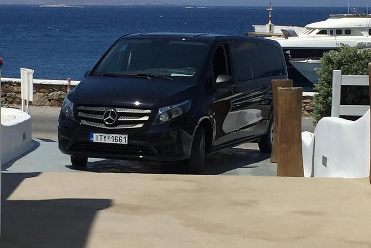 uma van preta estacionada em um estacionamento perto da água