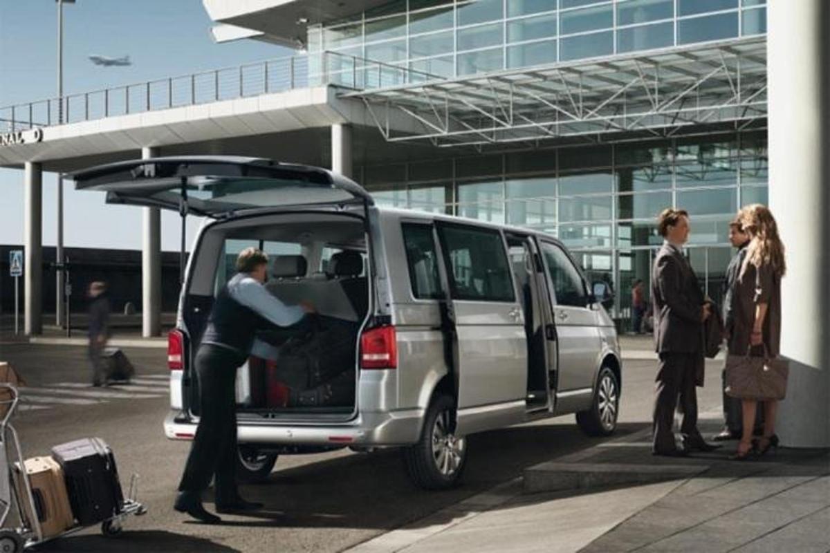 um grupo de pessoas em pé ao redor de uma van em um aeroporto