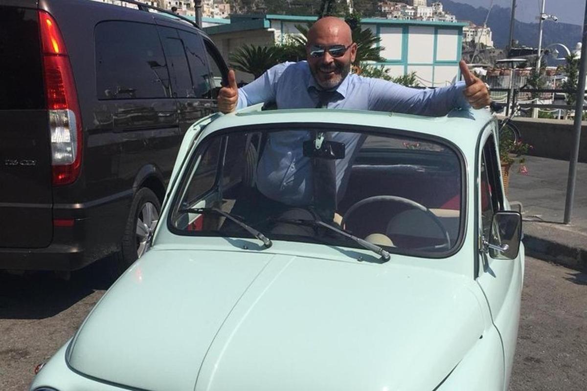 um homem fazendo sinal de positivo enquanto está sentado em um carro