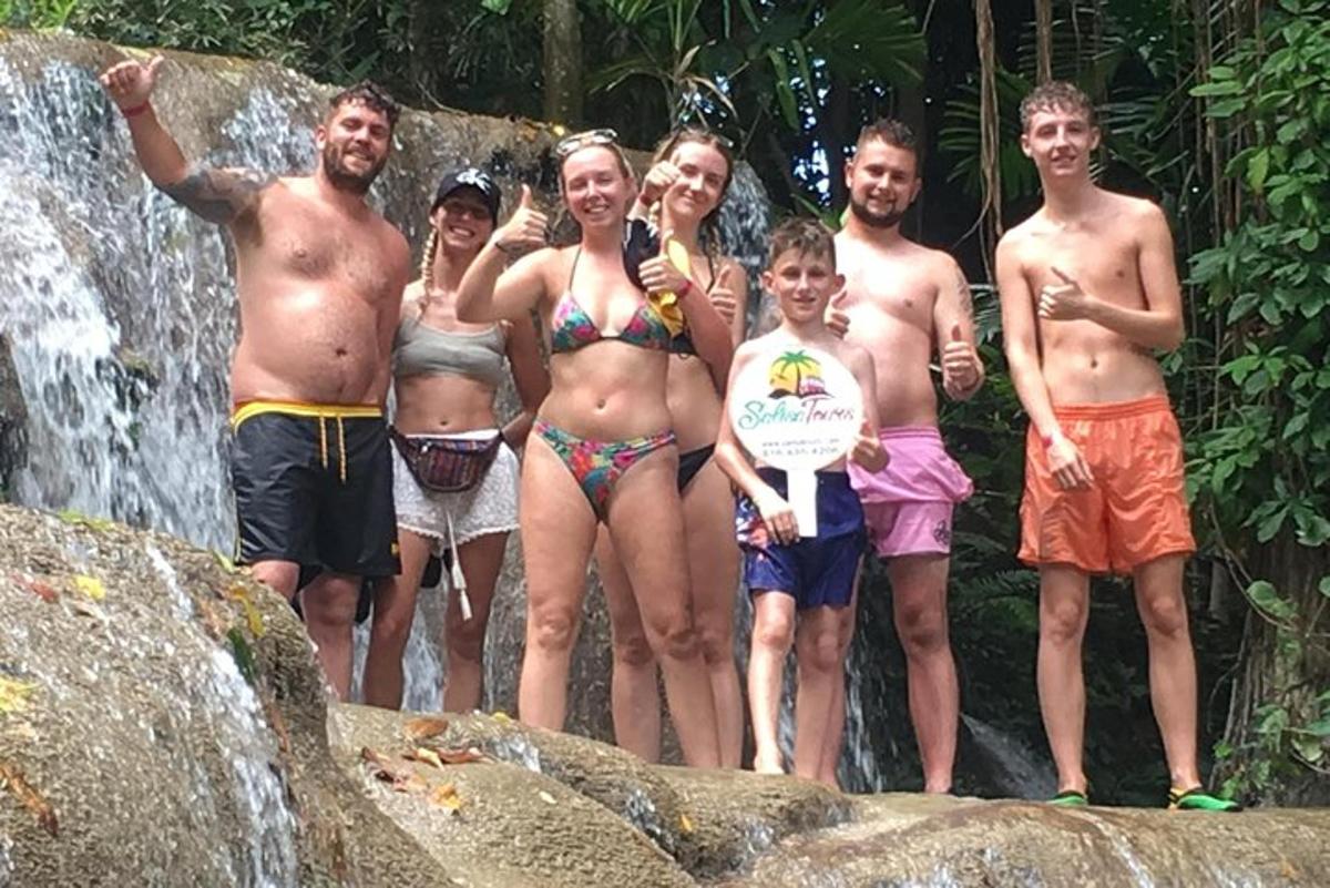 grupė žmonių, stovinčių priešais krioklį