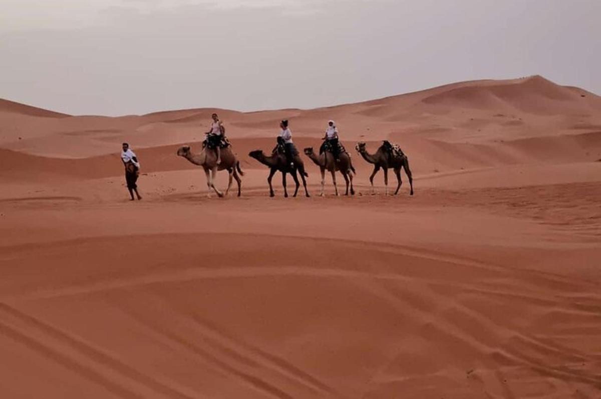 een groep mensen die te paard door de woestijn rijden