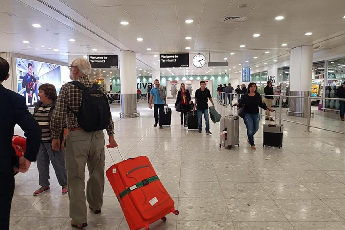 un gruppo di persone che camminano in un aeroporto con i bagagli