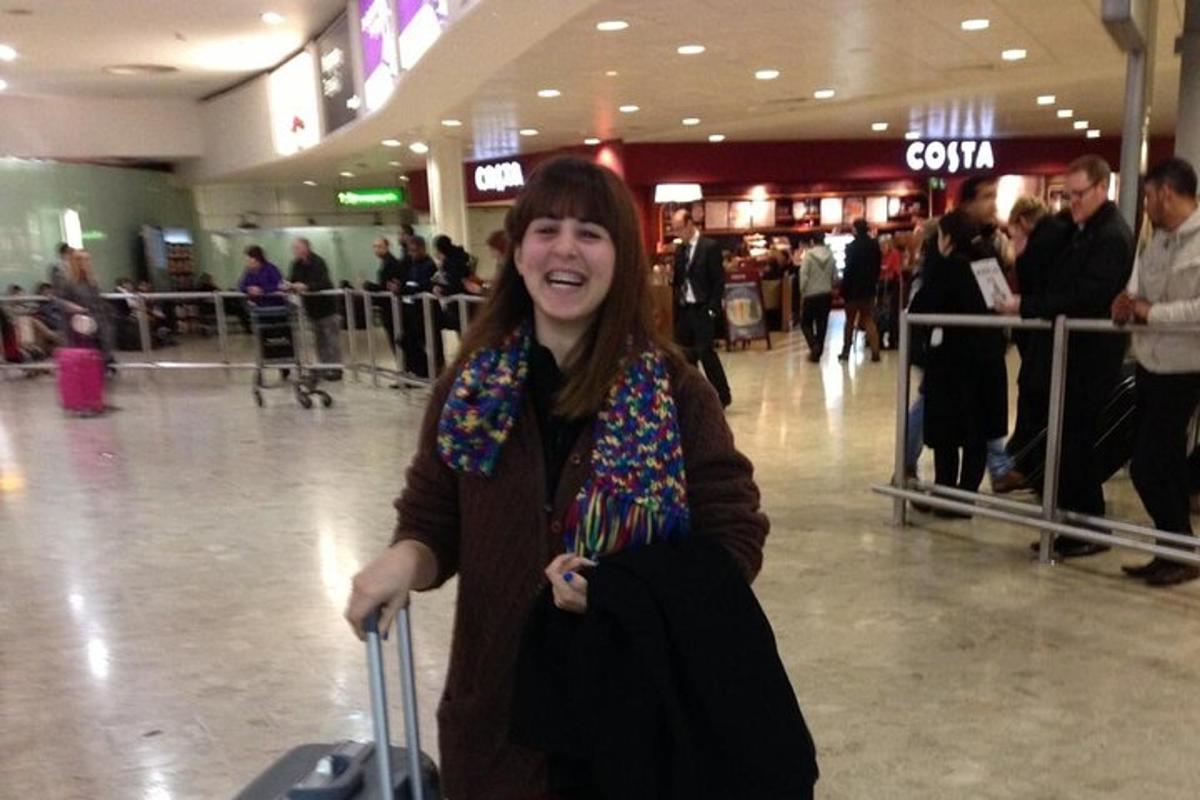 a woman standing in an airport with her luggage