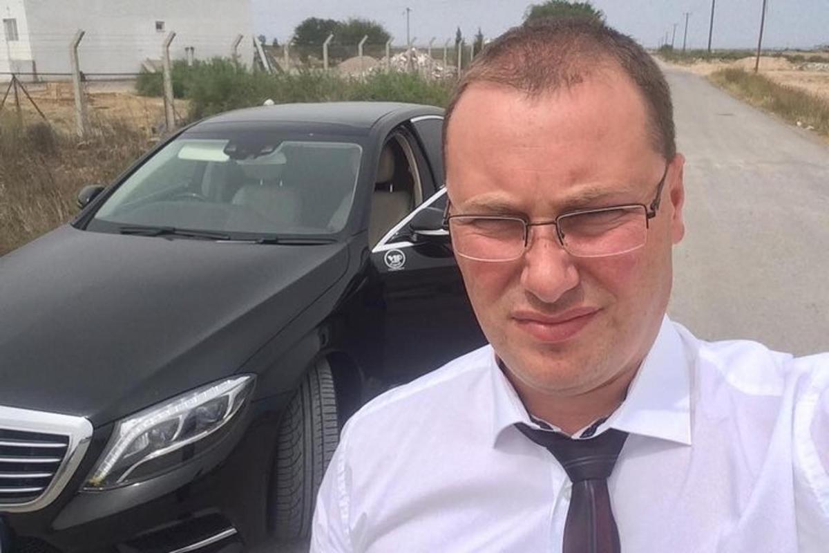 un uomo con gli occhiali e la cravatta in piedi accanto a un camion