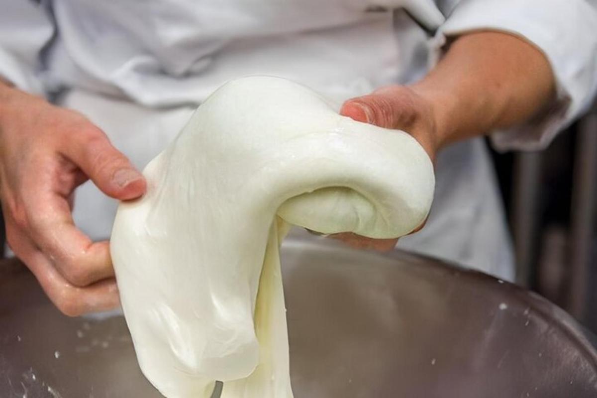 a person holding a piece of dough in a bowl
