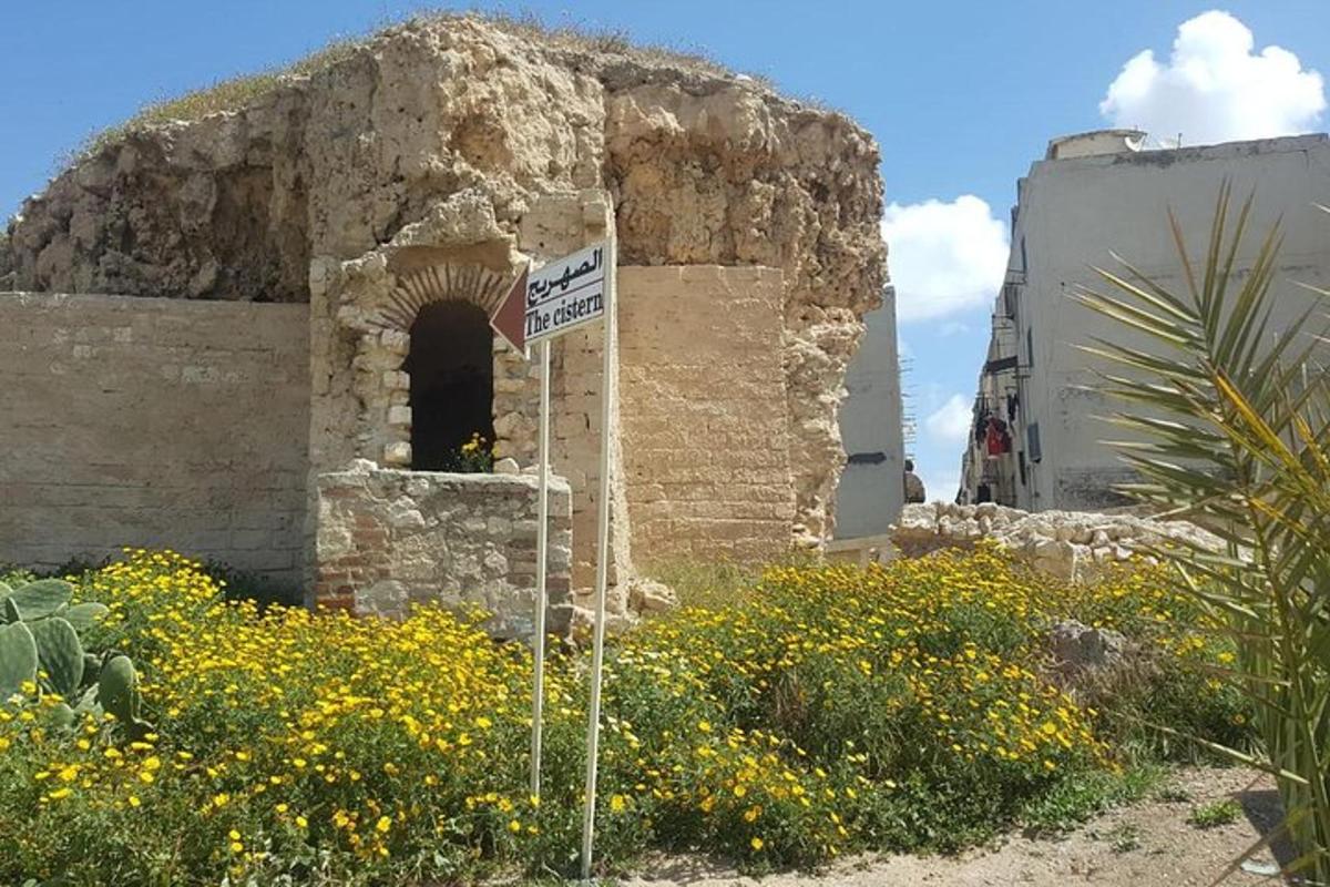 un antic edifici de pedra amb un rètol en un camp de flors