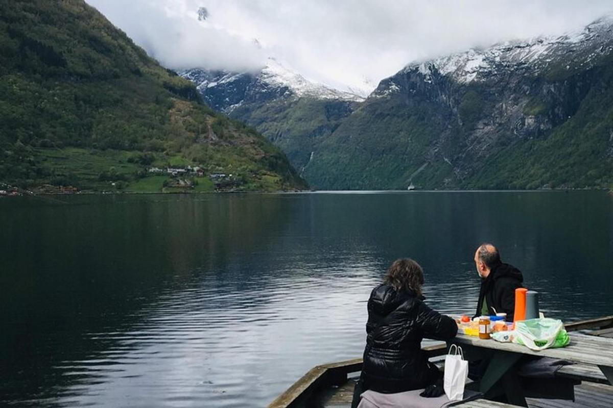 two people sitting at a table on a dock on a lake