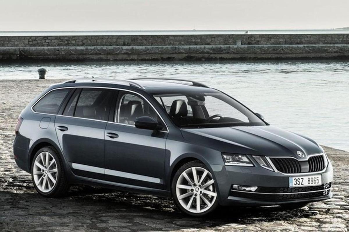 a gray car parked on a beach near the water