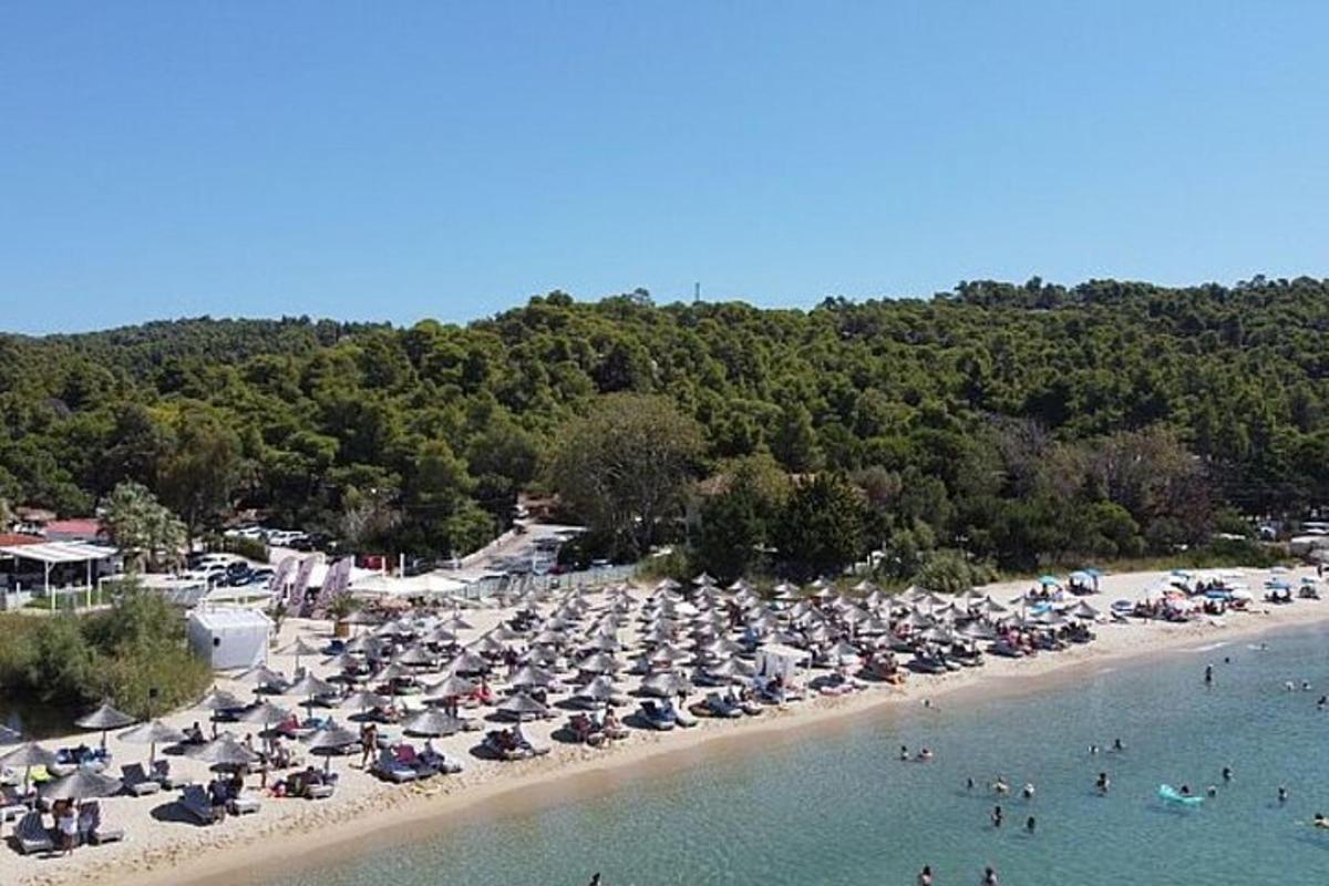 a beach with many umbrellas and people in the water