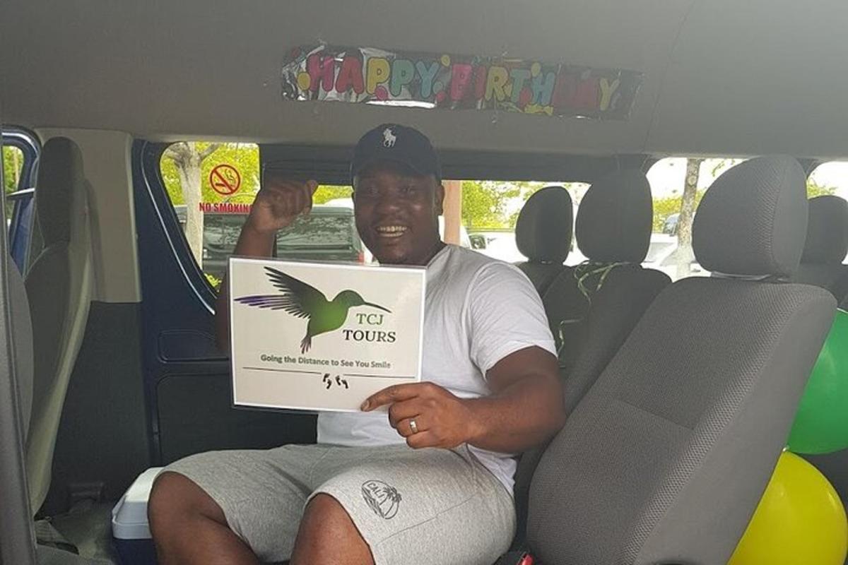 seorang lelaki duduk di belakang kereta sambil memegang komputer riba