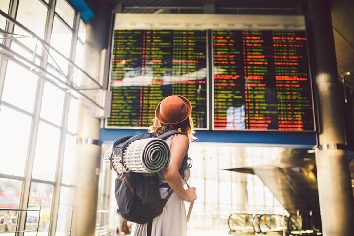 a woman with a backpack looking at a flight timetable