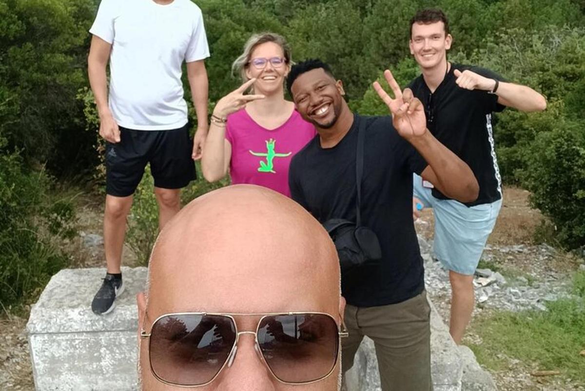 skupina ljudi, ki stojijo okoli moškega s sončnimi očali