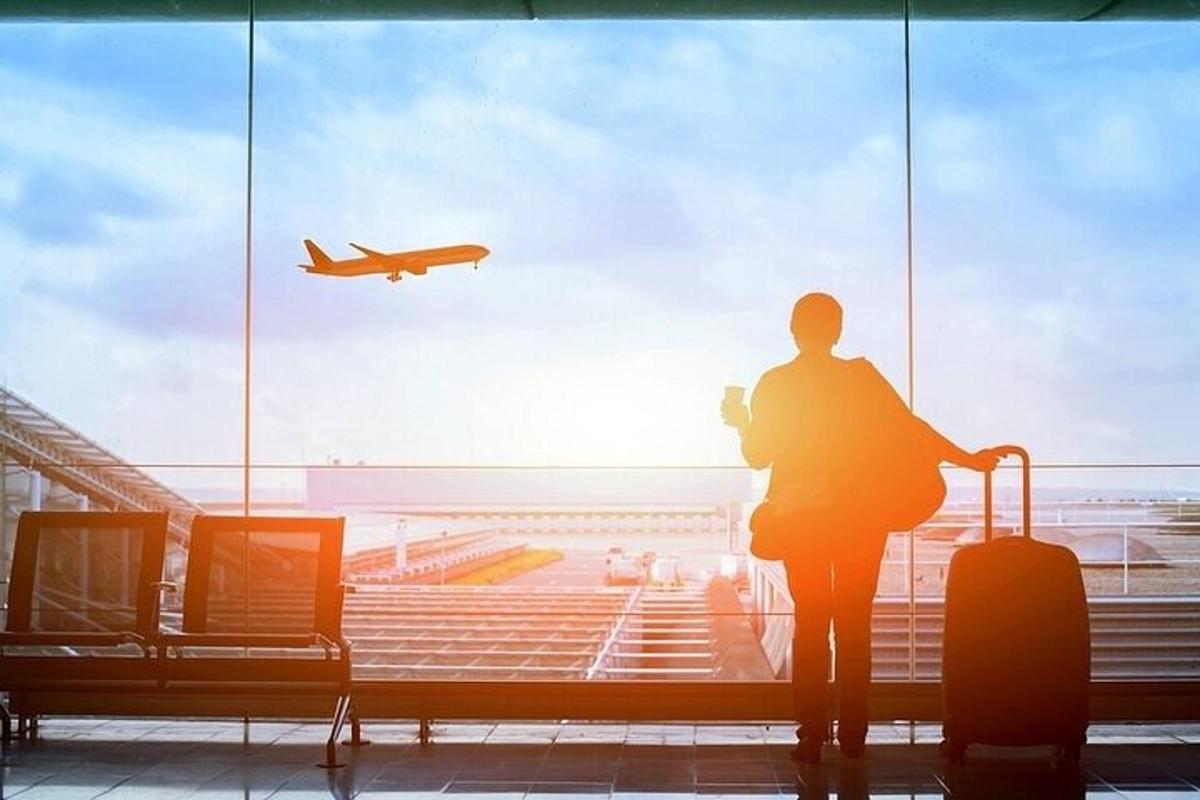 a person looking out of an airport window at an airplane