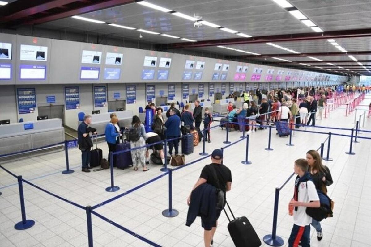 a crowd of people waiting in line at an airport