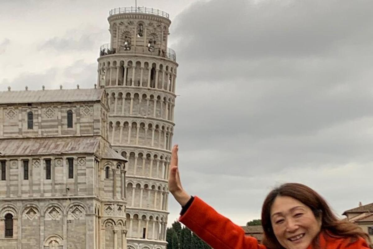 Una mujer parada frente a la Torre Inclinada de Pisa